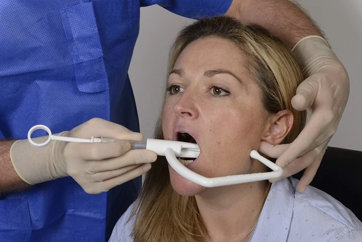 Le tube de l'angulateur et la seringue ainsi positionnés sont introduits dans la cavité orale.